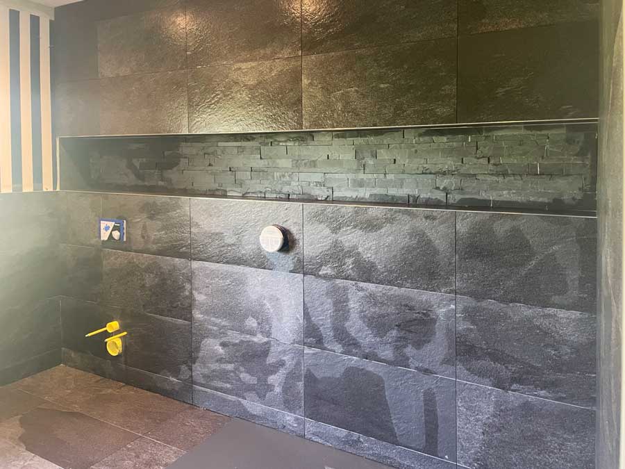 Contemporary, modern and dark coloured bathroom redesign underway in Giggleswick, Settle - showing construction of alcove with feature black stone spilt-face tiles.